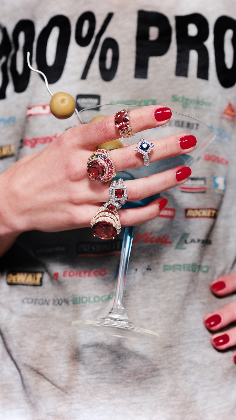 A woman holding a martini glass with 5 rings on her finger