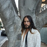 Jared Leto wears a Gucci shirt and pants, standing in front of a tree