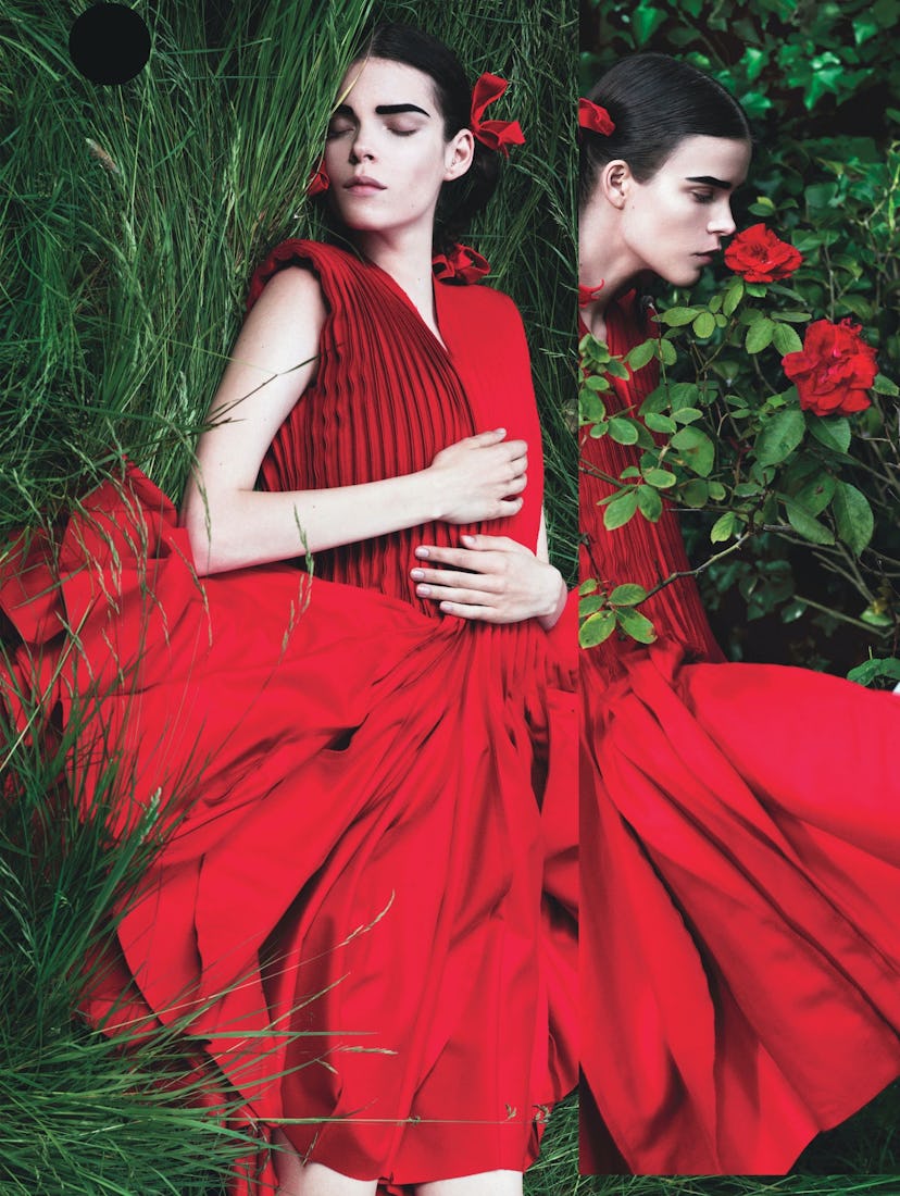 A model lying in the grass while wearing a red dress