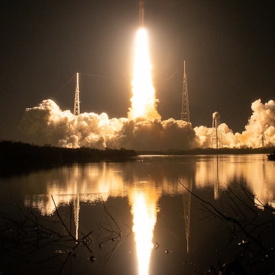 A rocket streaks into the sky with a blast of light behind it