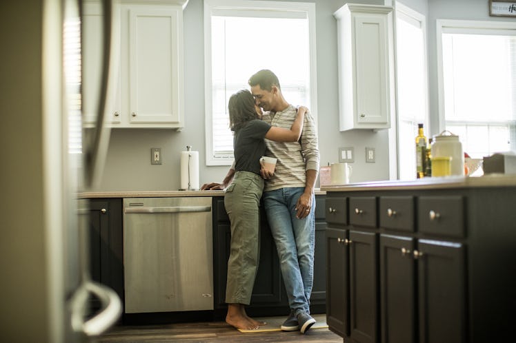 Husband and wife looking at one another tenderly in the kitchen