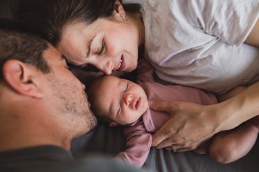 A mom and dad laying down with their newborn baby.