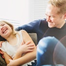 A dad and daughter laughing on a couch.