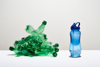 Reusable water bottle next to a stack of PET plastic bottles