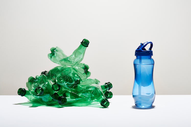 Reusable water bottle next to a stack of PET plastic bottles