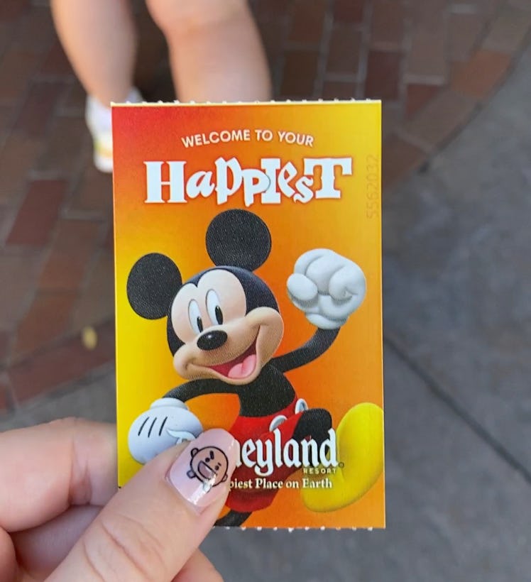 A woman holds a Disneyland theme park ticket, which the Disney Parks are becoming more expensive. 