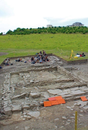 color photo of archaeologists excavating the foundations of a house