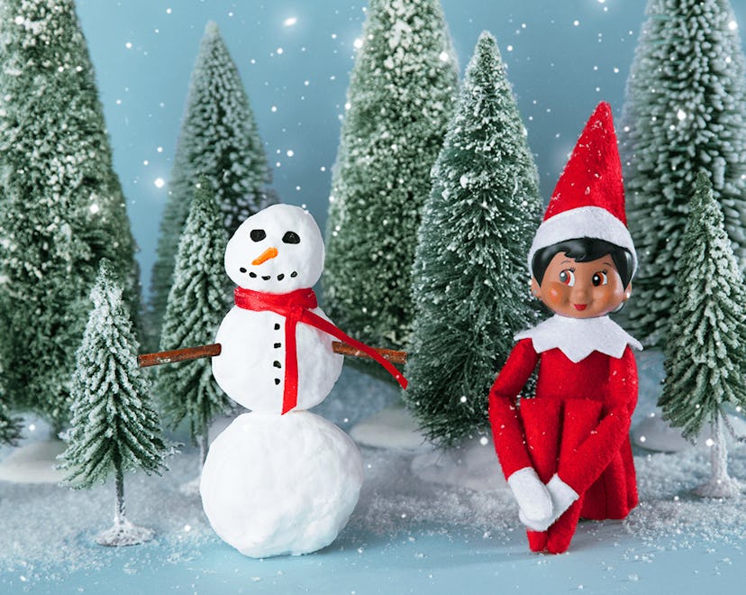 an elf on the shelf sitting in a winter scene in an article about elf on the shelf rules.