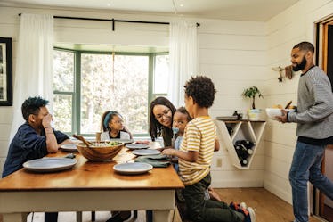 A dad walking in with a bowl to have a family dinner with his wife and kids.