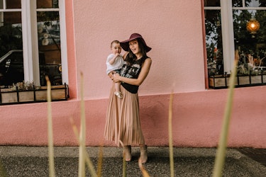 the author Anna McKenzie holding her baby daughter in front of a pink wall
