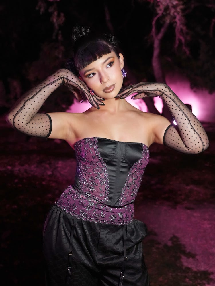Angela Aguilar wearing a tight black satin with purple lace top.