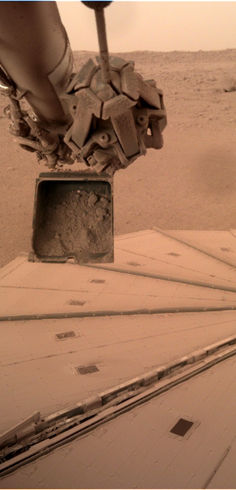 Mars InSight's dirt scoop and its solar panels in the background