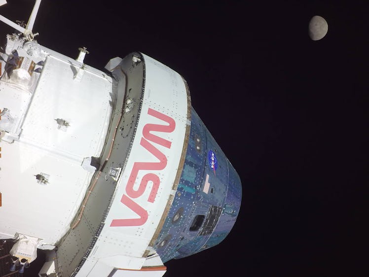 A white spacecraft with a cone-shaped head appears stark against the black backdrop of space. The Mo...