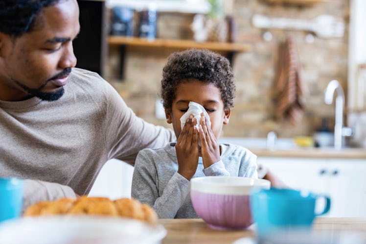 A dad with his arm around his sick child at the dinner table.