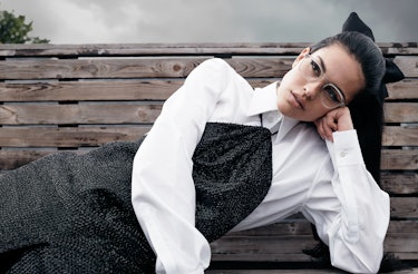 Model Amelia Gray wears glasses, white button down shirt and a dress.