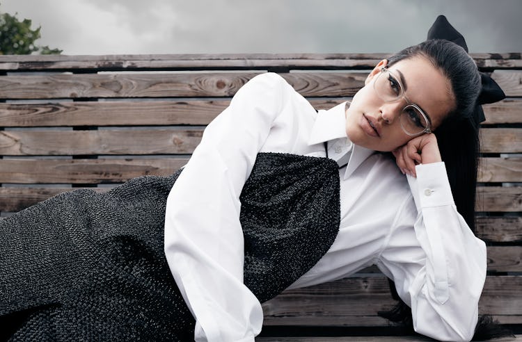 Model Amelia Gray wears glasses, white button down shirt and a dress.