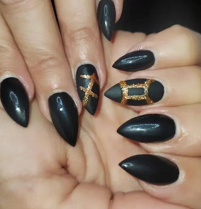 Sagittarius nail design with a gold astrological symbol on black, pointed nails