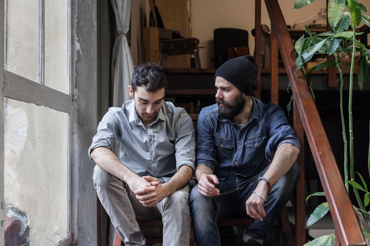 Two men sitting on stairs having a serious conversation