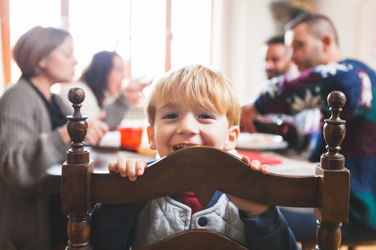 A child turned around on their chair during family dinner smiling at the camera
