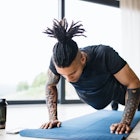 A man does pushups on a yoga mat at home.