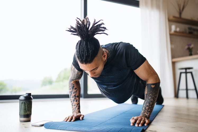 A man does pushups on a yoga mat at home.