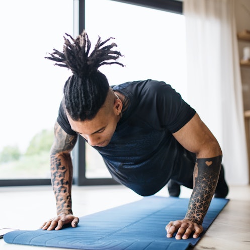 A man does pushups on a yoga mat at home.