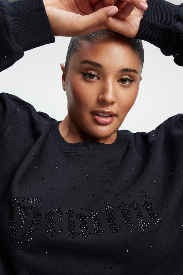 A model wears the black Gemini Boyfriend Sweatshirt from Khloe Kardashian's Good American Zodiac Col...