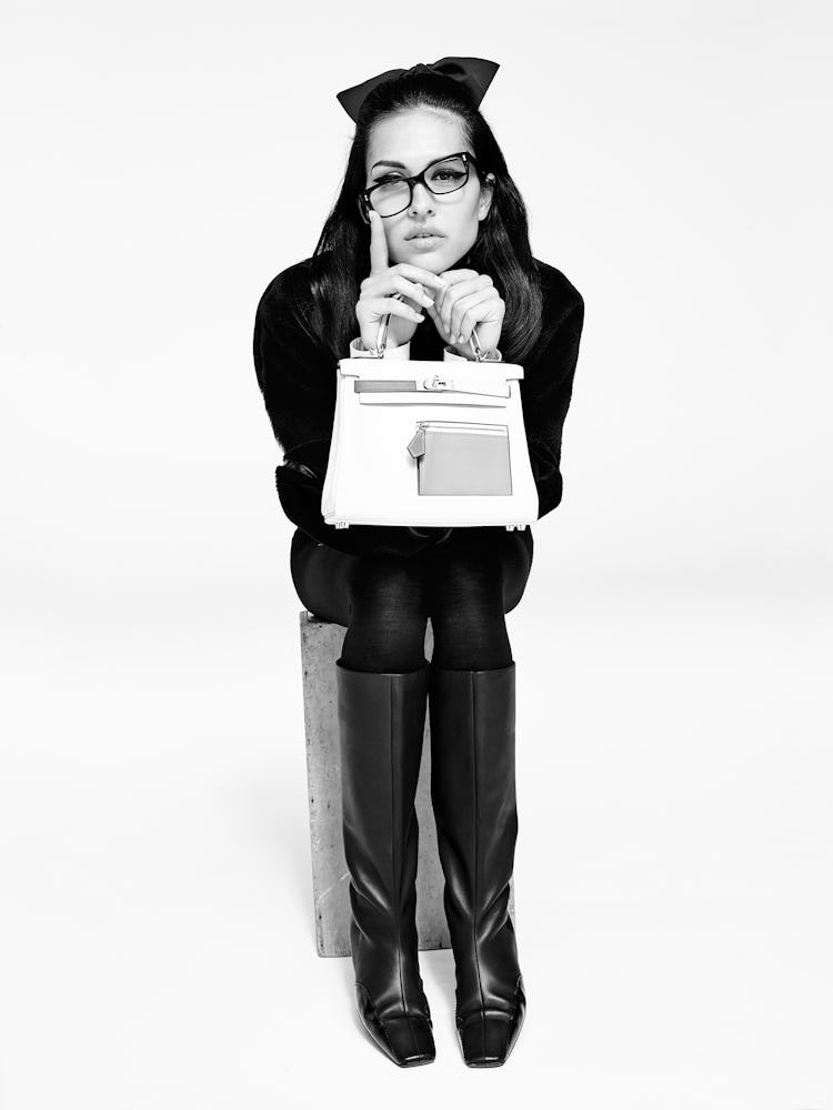 Model Amelia Gray wears black leather boots, glasses, purse and a black jacket.