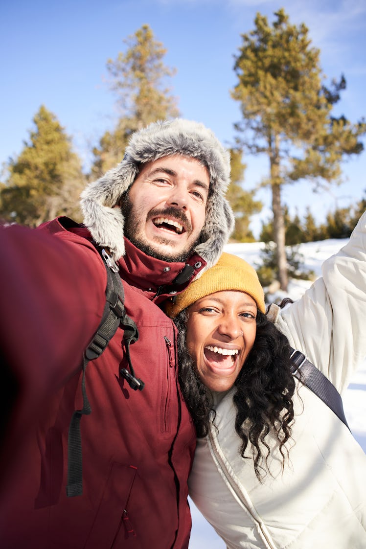 Young couple laughing in the snow on the most romantic day in December 2022.