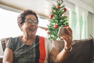 老妇人在圣诞树旁与家人视频通话