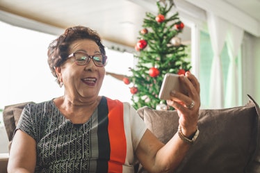老妇人在圣诞树旁与家人视频通话