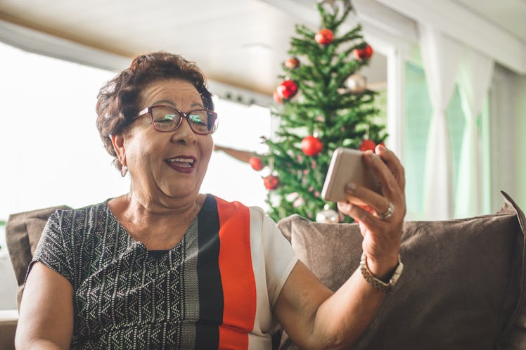 Elderly woman FaceTiming with family near Christmas tree