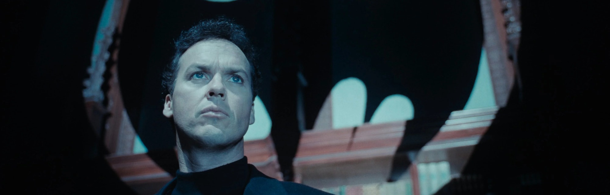 Bruce Wayne (Michael Keaton) stands beneath a Bat emblem in Tim Burton's Batman Returns