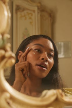 Dieux skin model applies cream in a mirror