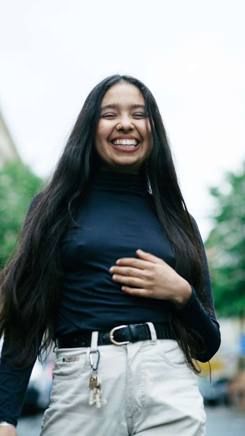 Young woman smiling and laughing as one of the luckiest zodiac signs in December 2022.