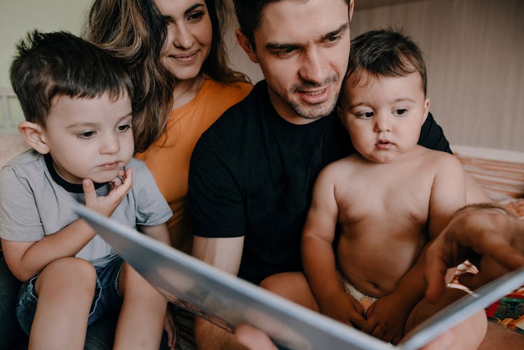 A mom and dad reading a book to their two kids