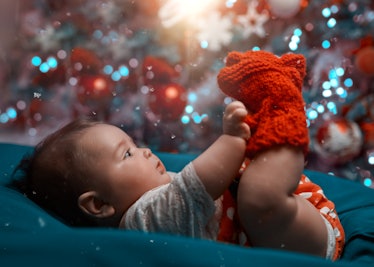 A newborn with a December birthday in front of a Christmas tree.
