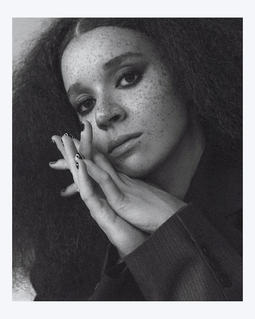 A black and white portrait of Erin with her hands clasped together by her face