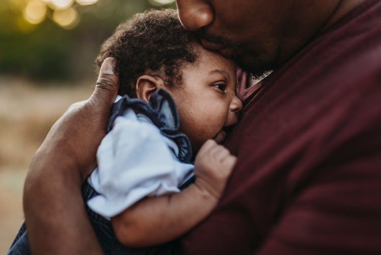 A dad holding his newborn baby to his chest.