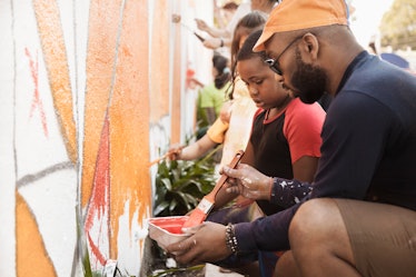 一个孩子和她的父亲志愿者通过绘画壁画墙。