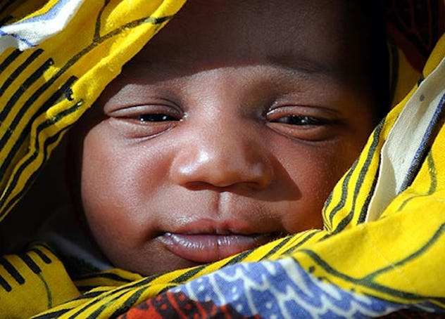 Close up of newborn baby swaddled in a yellow patterned blanket