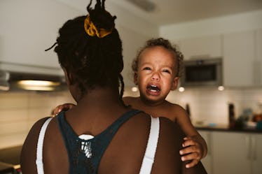 A mom holding a crying toddler.