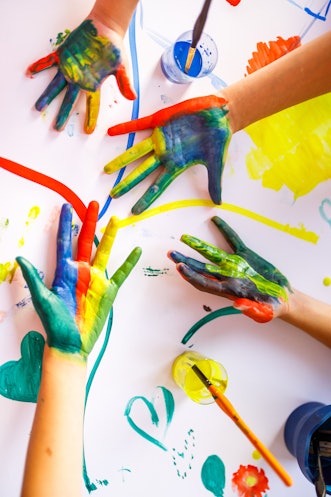 孩子们的手上涂着五颜六色的颜料，上面是手指画的背景。