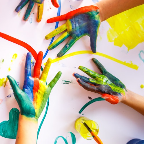 Children's hands with colorful paint on them, above a finger-painted background.