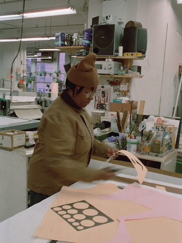 Nina in her studio working at a table with a ruler and stencil