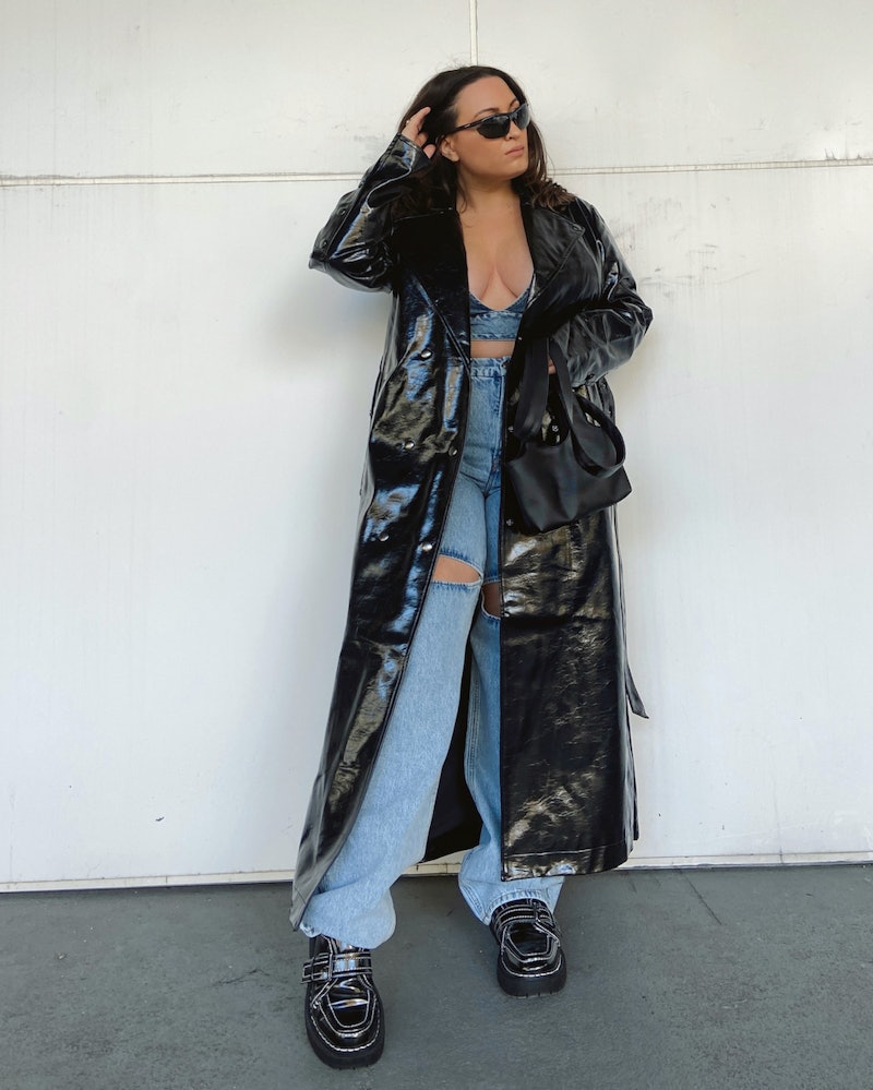 bella gerard poses in a black patent leather trench coat, denim bra, and loafers