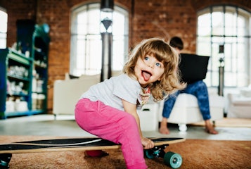 一个蹒跚学步的孩子在室内玩滑板。