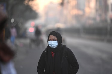 A woman wears a mask on a cold, smoggy November day in Delhi, India