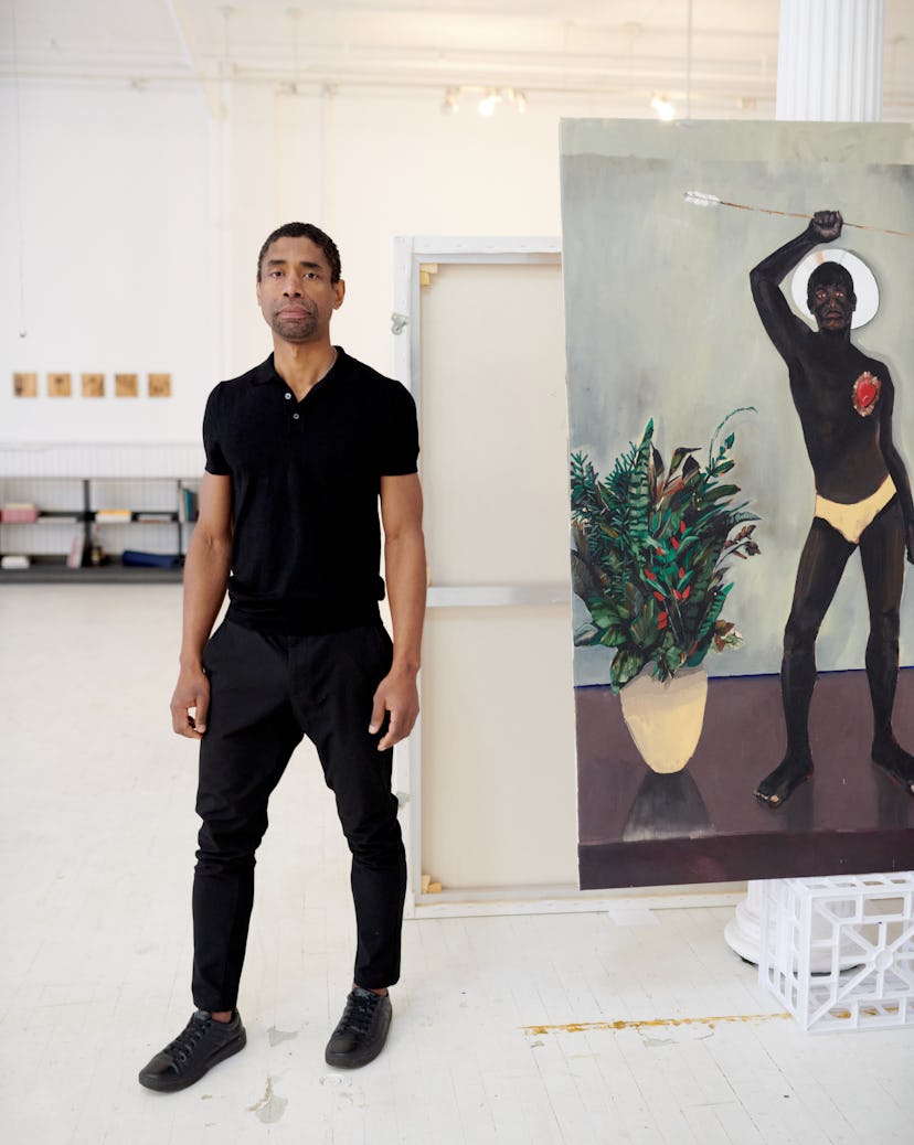 Antonio Obá standing next to his painting in his studio in SoHo NYC