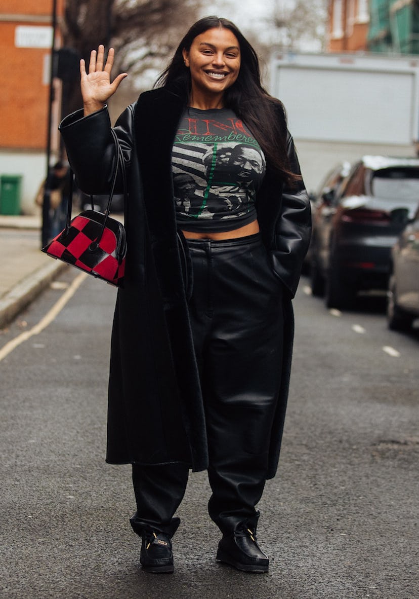 Model Paloma Elsesser waves and wears a black leather trench, black Martin Luther King Jr. shirt, bl...